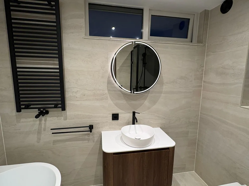 Badkamer met vrijstaand bad, badmeubel en ronde spiegel in Nieuwerkerk aan den IJssel