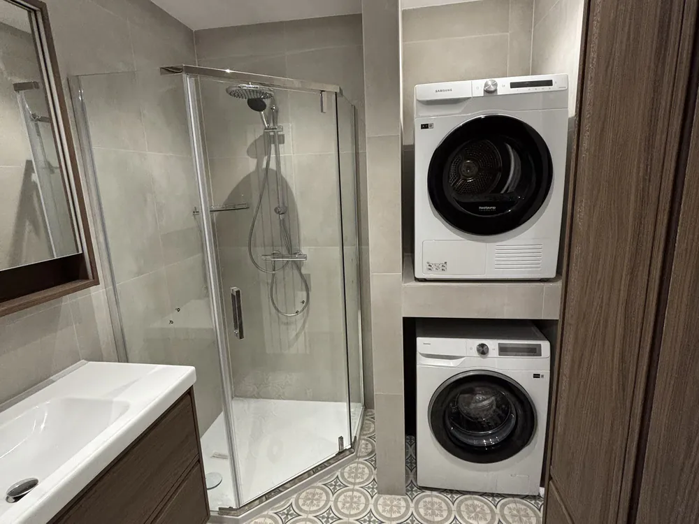 Badkamer met inloopdouche en wasmachine-opstelling in Oostvoorne