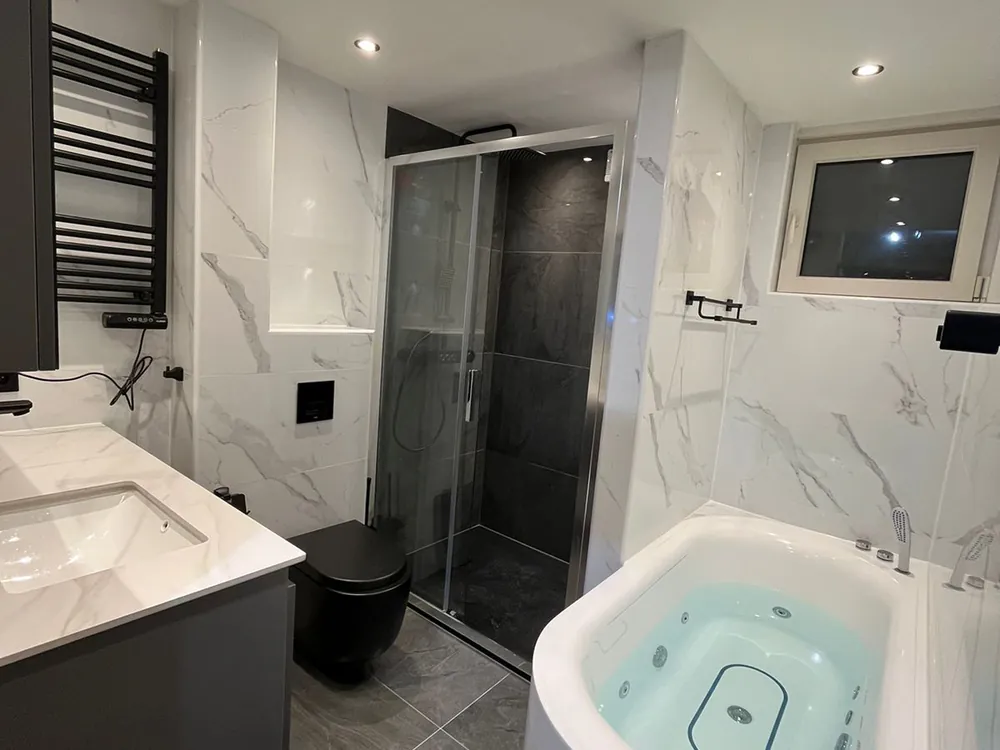 Badkamer met marmerlook tegels en whirlpoolbad